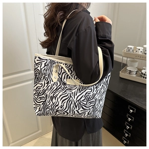 Détail de la couture latérale et de l'étiquette en cuir du grand sac fourre-tout zébré