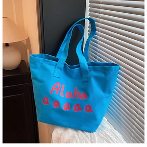 Détail du cabas en toile bleue avec texte rose Alaha aaaaa imprimé et texture douce