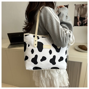 Détail d'un grand sac cabas à motif vache avec anses en cuir dans un bureau cosy