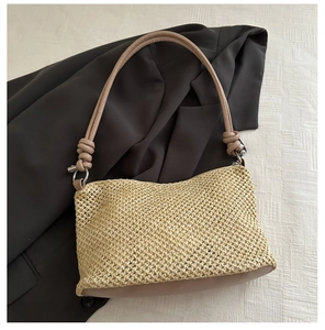 Detail view of woven straw shoulder bag with leather base and knotted strap detail