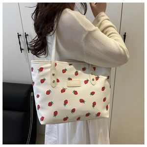 Détail du tote bag à imprimé fraise avec bretelles renforcées et patch logo jaune