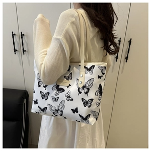 Détail du sac cabas blanc avec motif papillon noir et étiquette en cuir élégante
