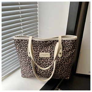 Détail du sac cabas léopard avec anses en cuir blanc et étiquette de mode élégante