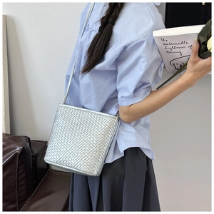 Detailed view of silver woven crossbody bag with metallic texture on a model shoulder