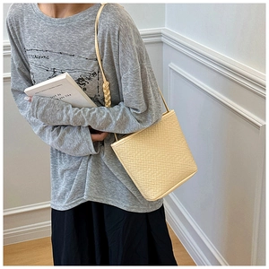 Detail of beige woven leather shoulder bag showing the rope knot texture and square design