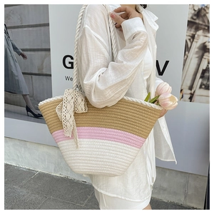 Detail of tricolor woven straw tote with rope handle and lace bow on a model