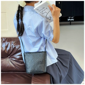 Detail showing the intricate hand-woven leather texture of this black bucket crossbody bag