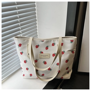 Détail d'un sac cabas en toile à imprimé fraises avec étiquette en cuir sur fenêtre