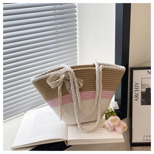 Detail of a tri-color woven bucket bag featuring lace bow and thick cotton rope handle