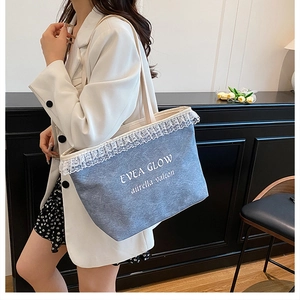 Detailed view of the blue denim tote bag featuring elegant white lace trim and text