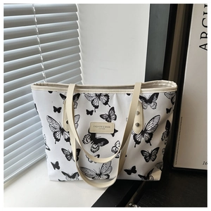 Détail d'un sac cabas blanc à motif papillon avec étiquette en cuir et fines lanières
