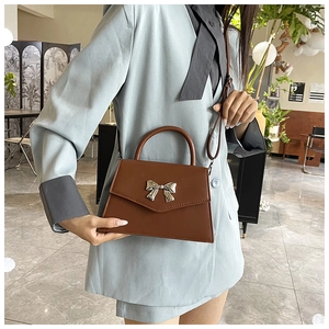 Brown crossbody bag with silver bow buckle worn over a light blue suit jacket