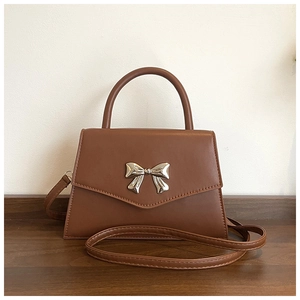 Close-up of brown faux leather handbag featuring a stylish silver metal bow decoration