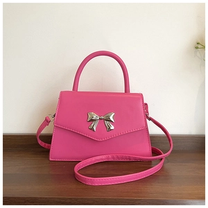 Detailed view of the rose pink handbag featuring a silver metal bow buckle and smooth texture