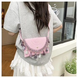 Detail of pink woven saddle bag with ethnic embroidery and colorful hanging tassels