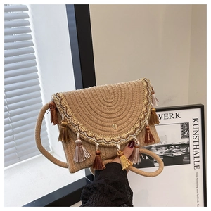 Detail of hand-woven straw saddle bag with fringe tassel and gold embroidery trim