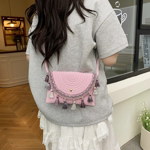 Pink woven saddle bag with purple geometric embroidery and tassel fringe details