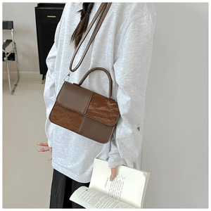 Fashionable color-block square crossbody bag carried by a model in a minimal setting