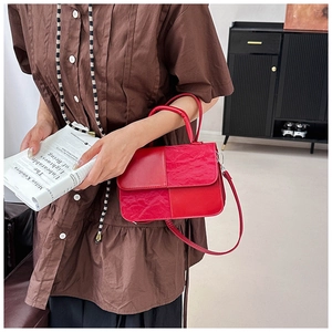 Detail view of red PU leather handbag featuring geometric paneling and pleated texture details