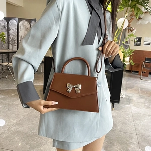 Brown faux leather crossbody bag with silver bow accent and top handle for women