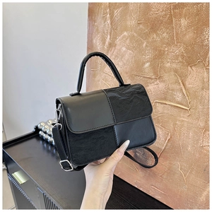 Detail of the stitching and dual-texture leather on the black geometric crossbody bag