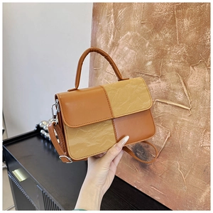 Detail of color-block patchwork tote featuring smooth and wrinkled leather textures