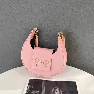 Close-up of pink crescent bag showing fine cross-grain texture and golden bow buckle
