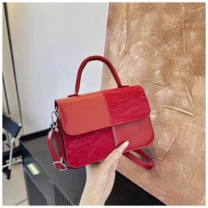 Detail of red square bag with textured patchwork panels and silver hardware accents