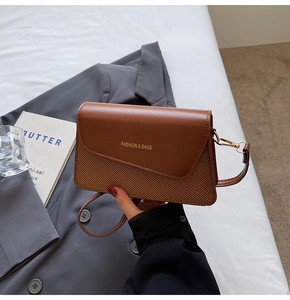 Detail of brown woven textured flap bag featuring Fashion & Bags lettering and slim strap
