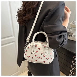 Détail du sac Boston blanc à imprimé cerises avec poignée et bandoulière porté par un mannequin
