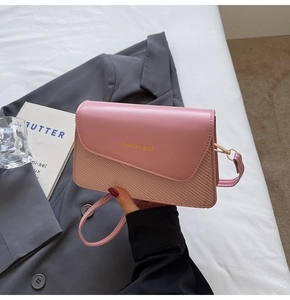 Macro detail of pink textured crossbody bag featuring gold Fashion & Bags lettering