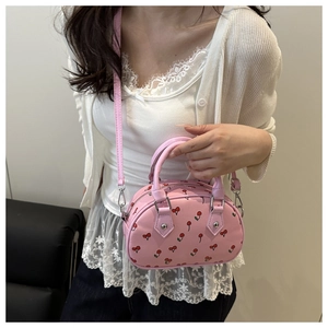 Détail d'un sac cabas rose imprimé cerises avec bandoulière et fermetures argentées