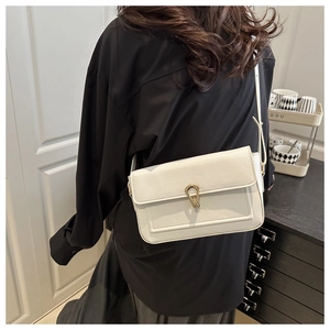 Détail du sac à bandoulière en cuir crème avec fermoir goutte doré élégant sur le rabat