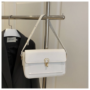 Détail d'un sac à bandoulière en cuir grainé blanc avec boucle métallique dorée en forme de U