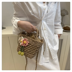 Detail of woven straw bag featuring pink crochet flowers and drawstring inner pouch