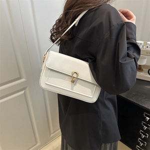 Sac à épaule chic en cuir grainé blanc avec fermoir doré porté par le mannequin
