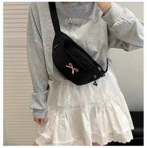 Gros plan du sac de poitrine en toile noire avec broderie nœud rose et sangle réglable