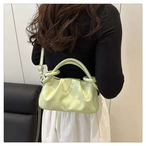 Détail du sac à bandoulière en cuir plissé vert clair porté par un mannequin pour le style