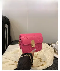 Detail of pink quilted crossbody bag with golden chain strap and metallic twist lock