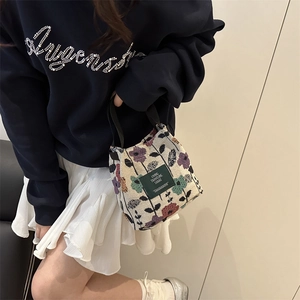 Floral tapestry tote bag with green label shown in a stylish casual lifestyle setting