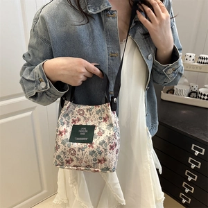 Retro floral canvas tote bag with black handles and green label in home setting