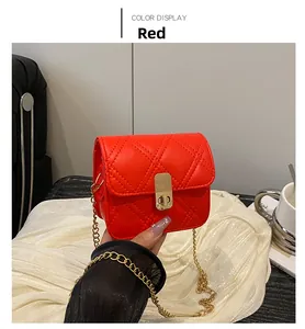 Detail of red quilted mini square bag with golden chain strap and rotary lock