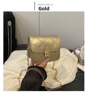 Detail of a mini gold crossbody bag with rhombic quilting and metallic chain strap