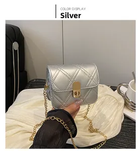Detail of silver mini quilted crossbody bag featuring a gold chain strap and metal lock