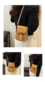 Detail of a brown suede crossbody bag with a round wooden decorative buckle