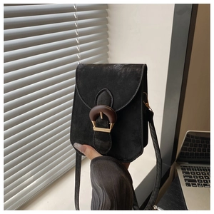 Close-up of a small vintage black crossbody bag with a large wood grain U-shaped buckle