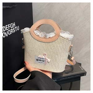 Détail d'un sac seau en paille tressé à la main avec bandoulière en cuir rose et dentelle