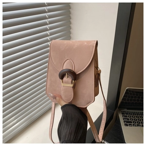 Detail of dusty pink crossbody bag featuring a matte finish and round wood texture buckle