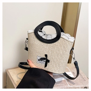 Détail du sac en paille blanc avec bordure en dentelle, nœud noir et anses en cuir