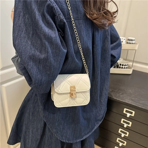 Quilted mini crossbody bag with gold chain strap in beige shown on a person